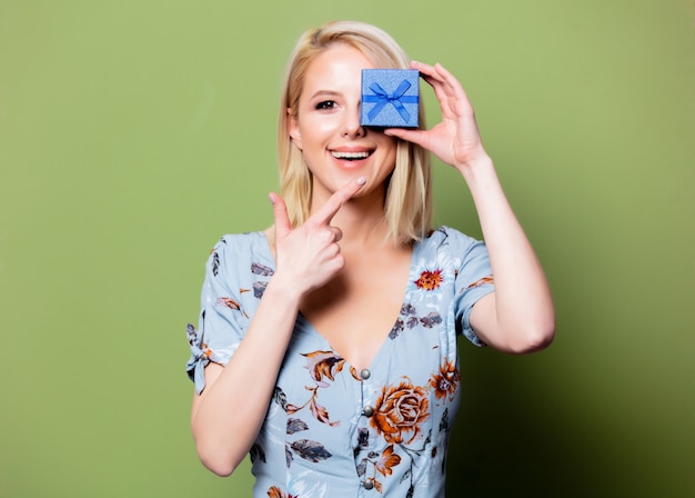 Blonde Frau mit Geschenkbox auf grüner Wand