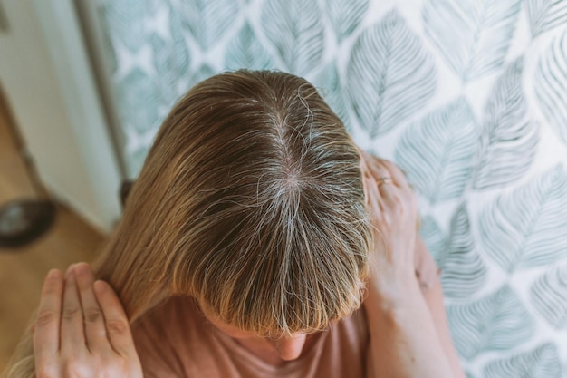 Blonde Frau mit grauem Haar, das gefärbt werden muss