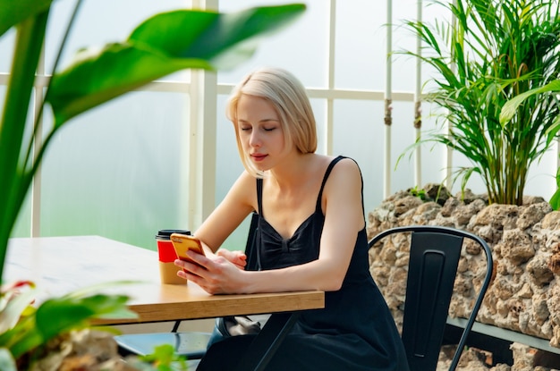 Blonde Frau mit Handy in einem Café