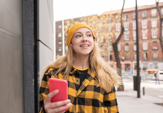 Blonde Frau mit kariertem Hemd und Handy in den gelben Farben der Straße
