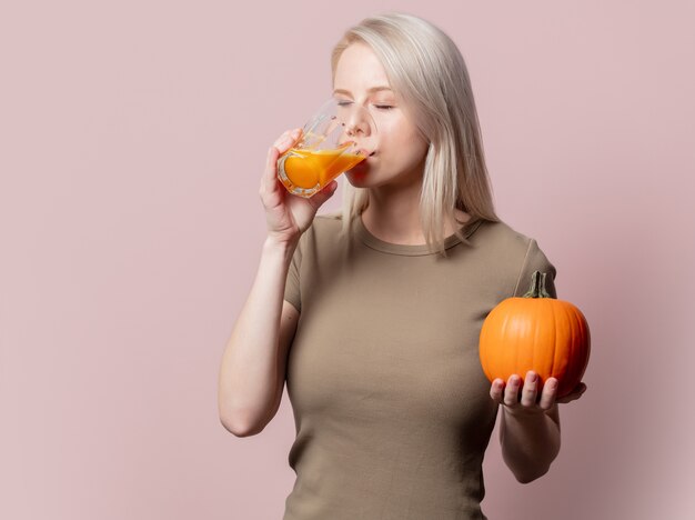 Blonde Frau mit Kürbissaft auf rosa