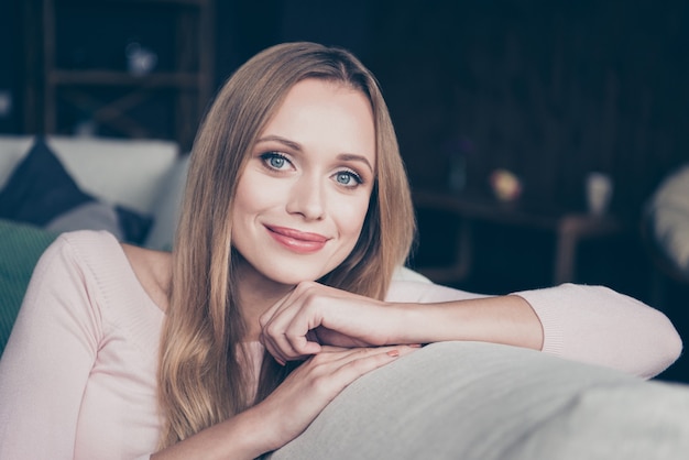 Blonde Frau mit langen Haaren, die drinnen im Wohnzimmer aufwirft