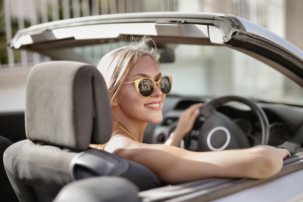 Blonde Frau mit Sonnenbrille fährt Auto