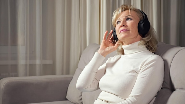 Blonde Frau mittleren Alters hört Musik über Kopfhörer