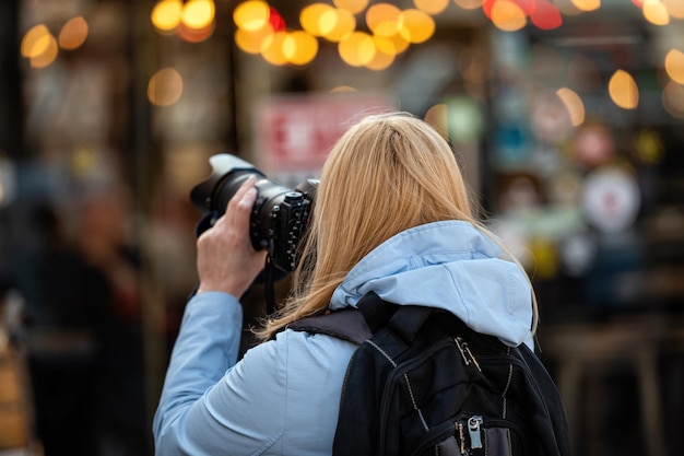 Blonde Frau mittleren Alters mit einer Kamera am Abend auf dem Lifestyle-Konzept der Straßen der Stadt