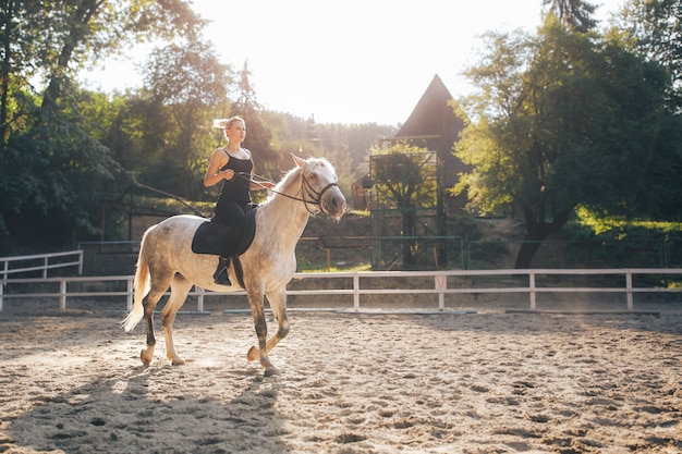 Blonde Frau reitet ein Pferd