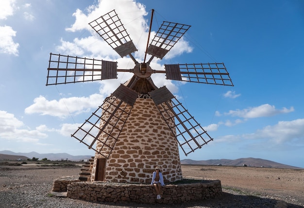 Foto blonde frau sitzt auf einer alten windmühle auf den kanarischen inseln von fuerteventura