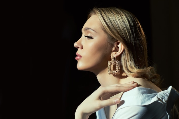 Blonde Frauen mit Schmuckohrringen in den Ohren in den Strahlen der Abendsonne