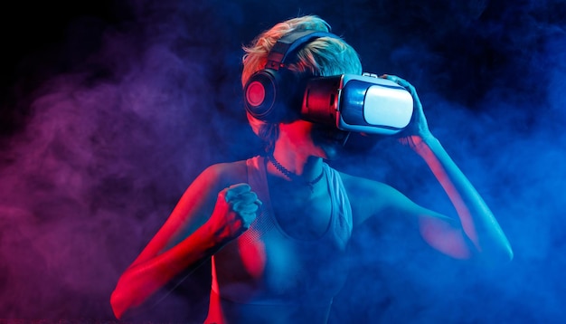 Blonde Hair Woman juega juegos de realidad virtual con Goggles, diviértete. La realidad virtual es la conexión de juegos del futuro.