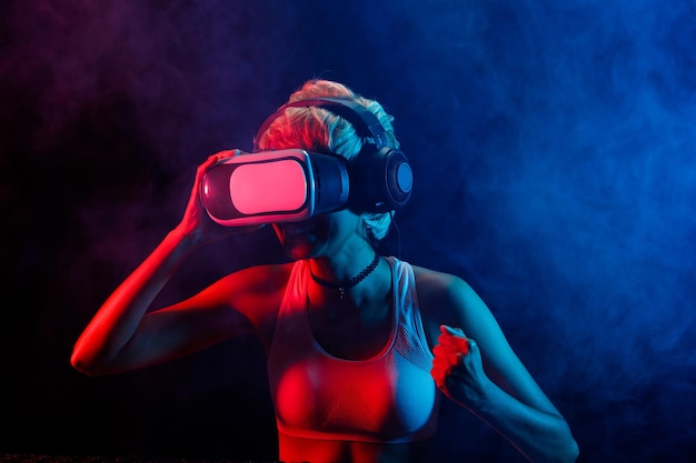 Blonde Hair Woman juega juegos de realidad virtual con Goggles, diviértete. La realidad virtual es la conexión de juegos del futuro.