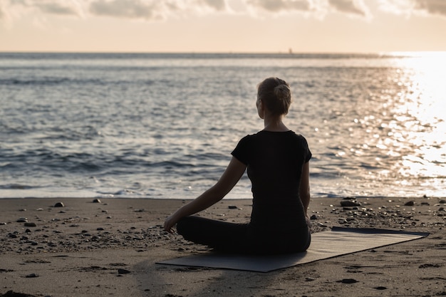 Blonde hermoso de la mujer joven en hacer yoga negro