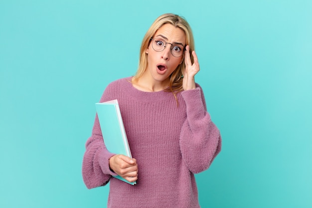 Foto blonde hübsche frau, die bücher hält. studentisches konzept