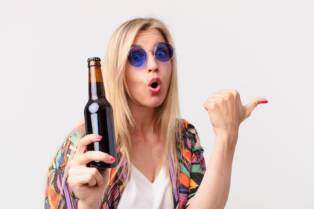 Blonde hübsche Frau, die ein Bier trinkt. Sommerkonzept