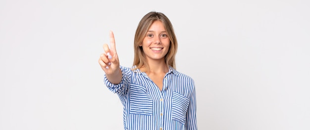 Foto blonde hübsche frau, die lächelt und freundlich aussieht, die nummer zwei oder die zweite mit der hand nach vorne zeigt und herunterzählt