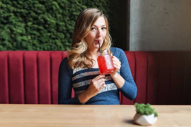 Blonde hübsche Frau, die Limonade im Café trinkt.