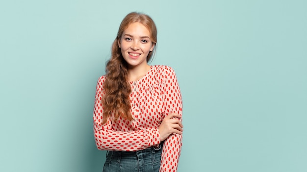 Blonde hübsche Frau, die schüchtern und fröhlich lacht, mit einer freundlichen und positiven, aber unsicheren Haltung