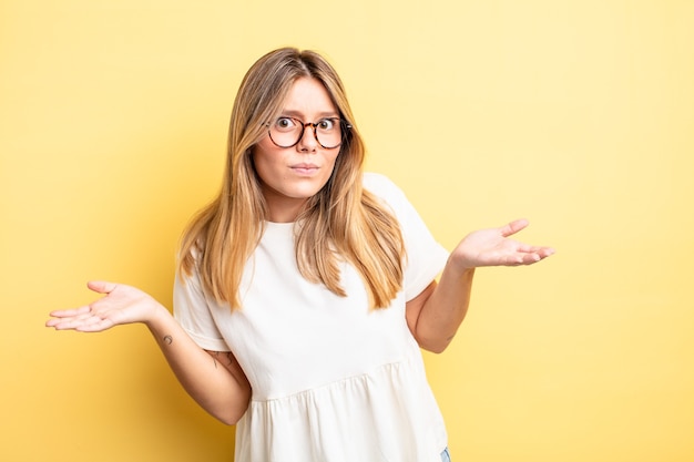 Blonde hübsche Frau, die sich ahnungslos und verwirrt fühlt, keine Ahnung hat, absolut verwirrt mit einem dummen oder törichten Blick