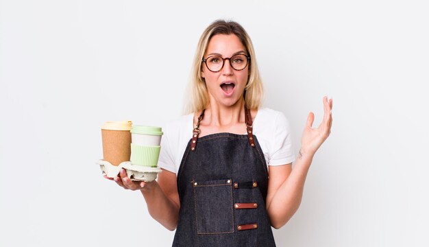 Blonde hübsche Frau, die sich glücklich und erstaunt über etwas unglaubliches Kaffeekonzept zum Mitnehmen fühlt