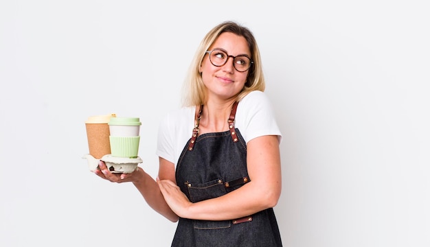 Blonde hübsche Frau, die sich verwirrt und unsicher mit den Achseln zuckt, Kaffeekonzept zum Mitnehmen