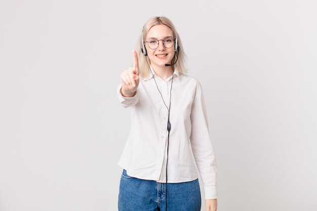 Blonde hübsche Frau, die stolz und selbstbewusst lächelt und das Telemarketing-Konzept Nummer eins macht