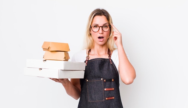 Blonde hübsche Frau, die überrascht aussieht, als sie eine neue Idee oder ein Konzept zum Mitnehmen von Fast Food realisiert