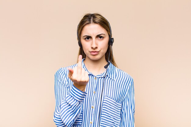 Blonde hübsche Frau, die wütend, genervt, rebellisch und aggressiv ist, den Mittelfinger bewegt und sich wehrt