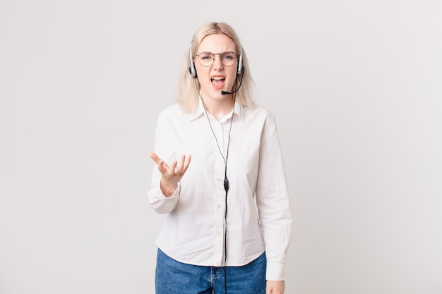 Blonde hübsche Frau, die wütendes, verärgertes und frustriertes Telefonmarketingkonzept schaut