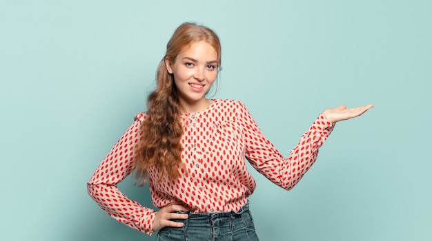 Blonde hübsche Frau lächelt, fühlt sich sicher, erfolgreich und glücklich, zeigt Konzept oder Idee auf Kopienraum auf der Seite