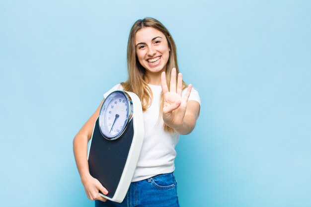 Blonde hübsche Frau lächelt und sieht freundlich aus, zeigt Nummer vier oder vierten mit der Hand nach vorne, Countdown