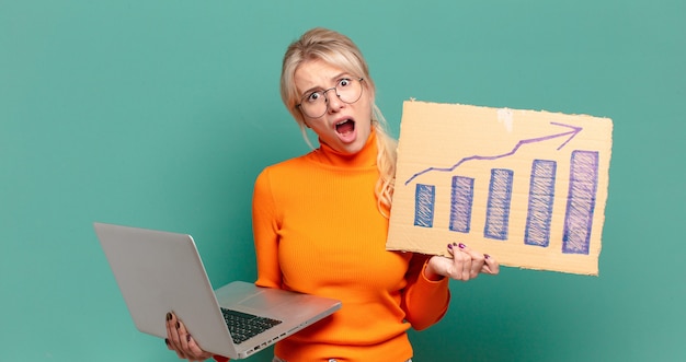 Blonde hübsche Frau mit einer zunehmenden Balkengrafik und einem Laptop