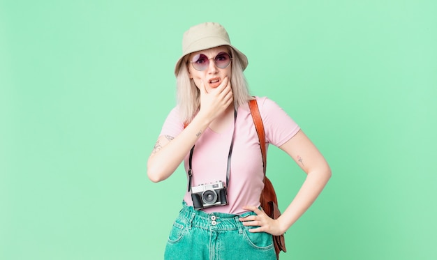 Blonde hübsche Frau mit weit geöffnetem Mund und Augen und Hand am Kinn. Sommerkonzept