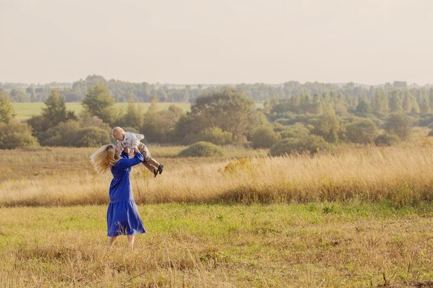 Blonde junge Frau im blauen Kleid im Feld bei Sonnenuntergang