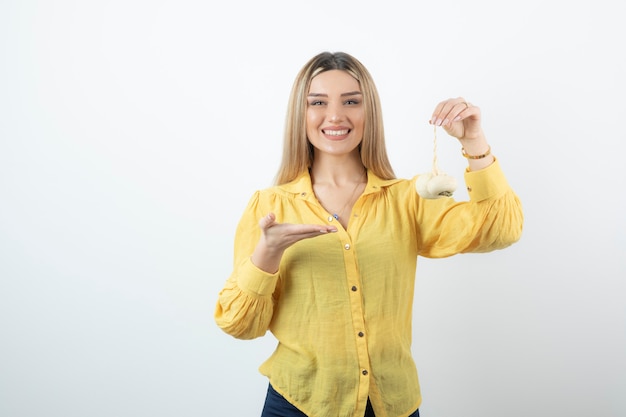 Blonde junge Frau in der gelben Bluse mit den weißen Rüben stehend