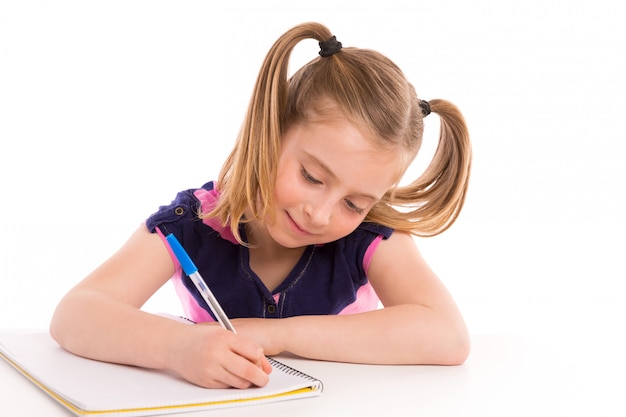 Blonde kinderstudentin mit gewundenem notizbuch im schreibtisch