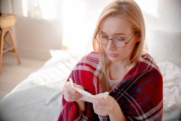 Blonde kranke Frau mit Coronavirus-Symptomen