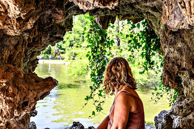 Blonde lockige Frau sitzend mit Blick auf den See des Parque del Retiro in Madrid, Spanien.