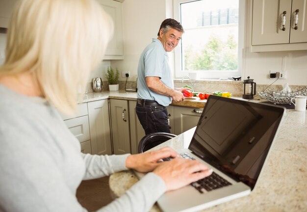 Blonde maduro feliz com laptop falando com marido