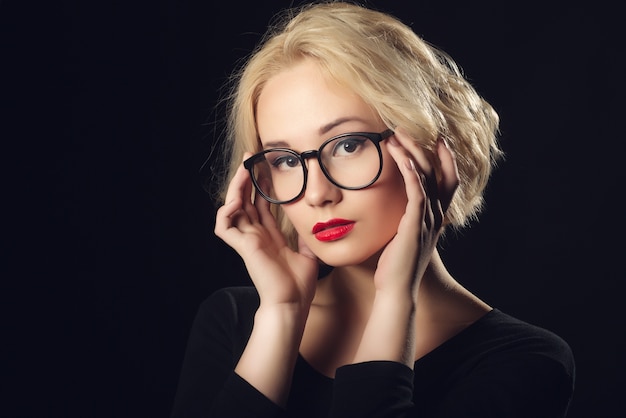 Blonde Mädchenfrau mit Brille auf dunkel