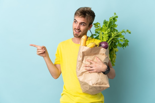 Blonde Person, die eine Tüte Essen zum Mitnehmen nimmt, zeigt zeigenden Finger zur Seite