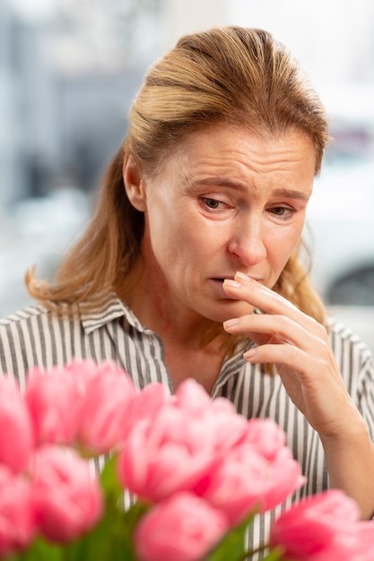 Blonde reife Frau, die allergisch ist, nachdem sie Blumen vom Ehemann erhalten hat