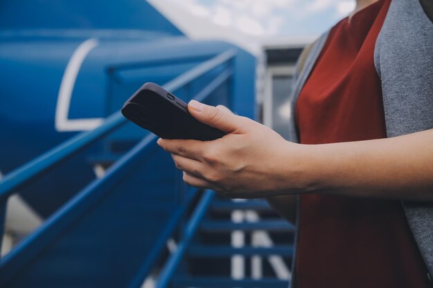 Blonde Touristin überprüft eingehende Benachrichtigungen auf dem Smartphone sitzt auf dem Sitz des Flugzeugs mit NetbookJunge Geschäftsfrau teilt Medien vom Telefon auf dem Laptop während des Fluges