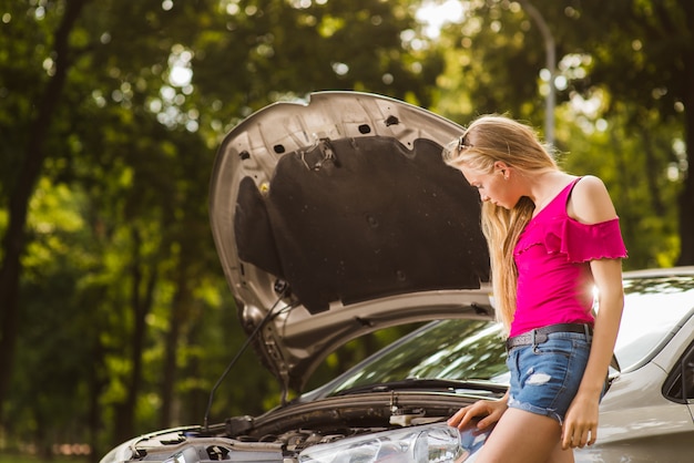 Blonde traurige Frau nahe offenem Auto