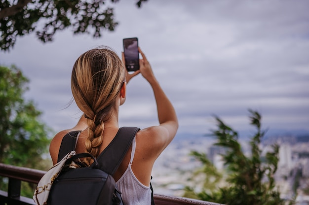 Blonde Wandererfrau des Reisenden, die Fotos von der Aussichtsplattform übersehend das Stadtzentrum machend geht. Reiseabenteuer in China, touristischer schöner Bestimmungsort Asien, Sommerferien-Urlaubsreise