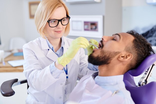 Foto blonde zahnärztin arbeitet mit einem patienten