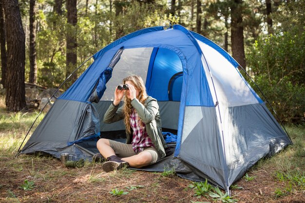 Blonder Camper, der durch Ferngläser schaut