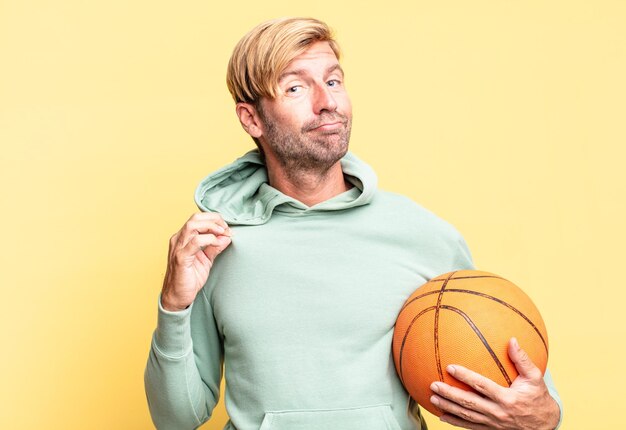 Blonder gutaussehender erwachsener Mann mit einem Basketballball