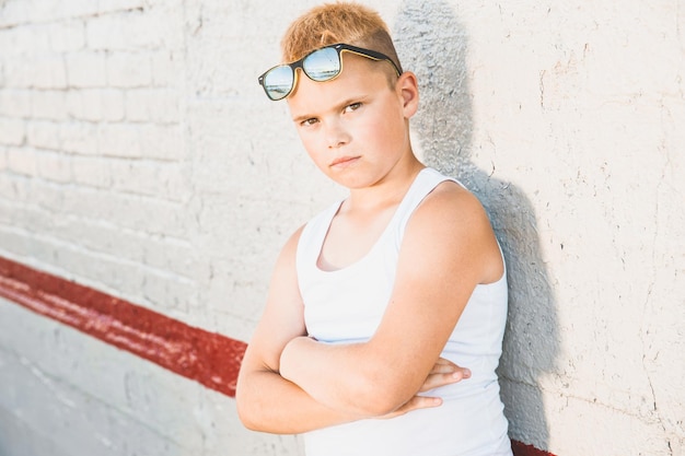 Foto blonder junge in einem weißen t-shirt mit sonnenbrille auf dem kopf. nahaufnahmeporträt