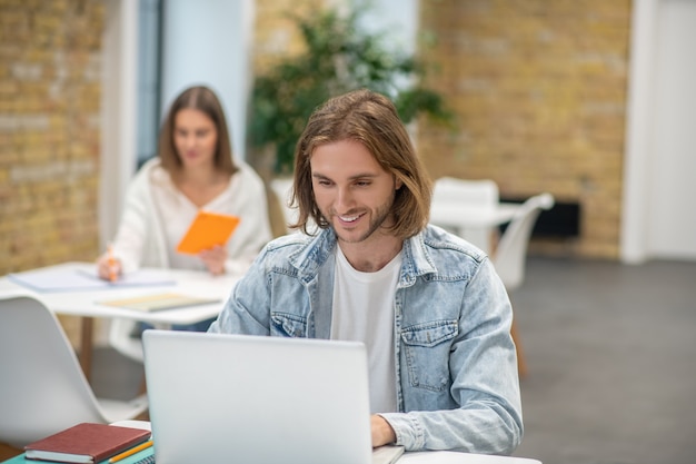 Blonder junger Mann, der am Laptop sitzt und beteiligt schaut