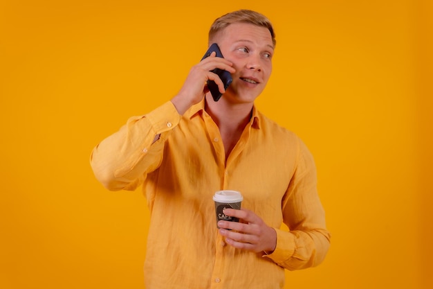 Blonder kaukasischer Mann auf gelbem Hintergrund, der mit dem Telefon telefoniert