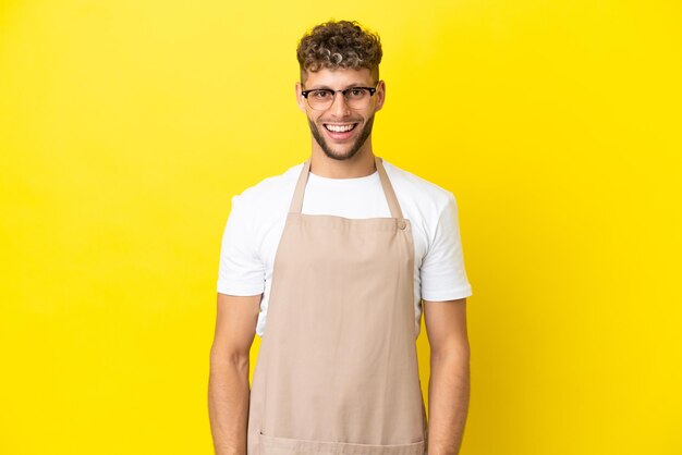 Blonder Mann des Restaurantkellners lokalisiert auf gelbem Hintergrund mit überraschendem Gesichtsausdruck